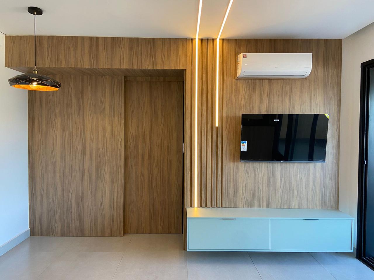 Painel de TV amadeirado com iluminação embutida em dormitório