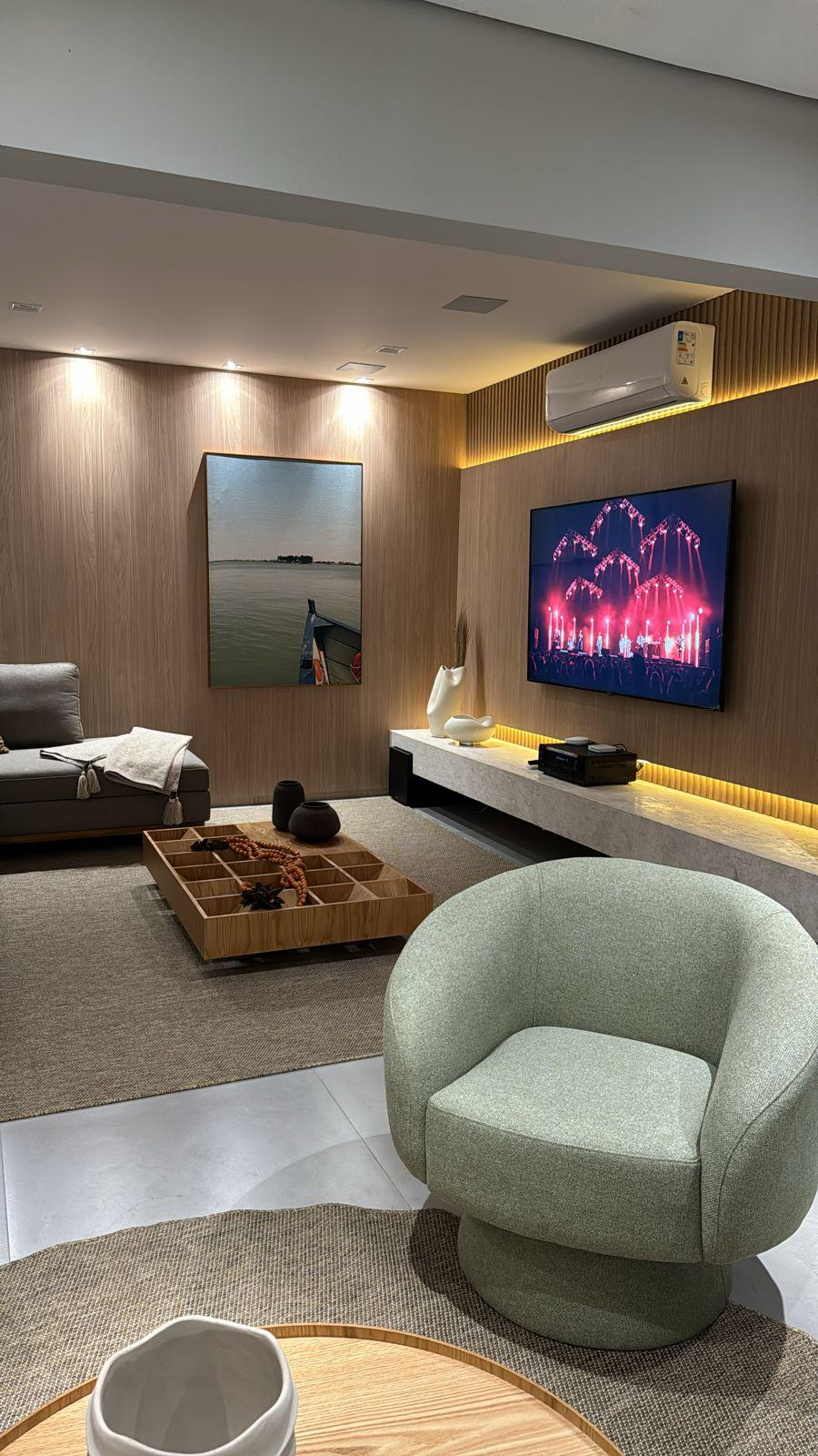 Sala de estar com painel ripado, iluminação indireta e poltrona
